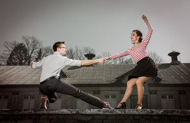 young couple dancing swing outside in front of old brick house