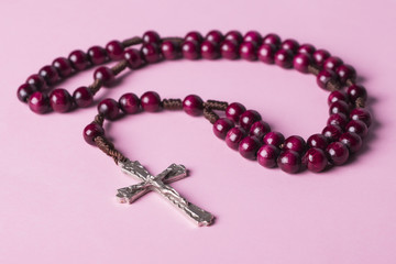 Rosary on a pink background. Christian cross.