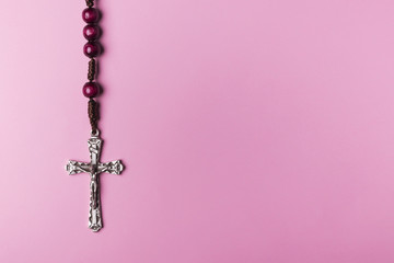 Rosary on a pink background. Christian cross.