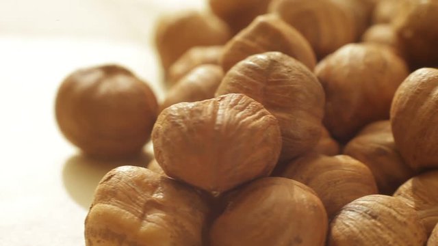 Plenty of peeled hazelnuts on white background macro video