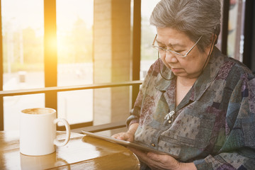 Senior woman sitting and resting in cafe coffee shop using digital tablet computer. social networking concept