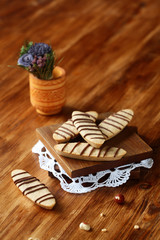 Hazelnut Long Cookies decorated with chocolate treads, on wooden board, on wooden background.