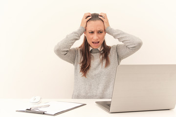 A woman sits in the office holding her head