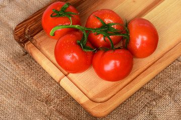 Tomatoes on vine on cutting board. burlap background. cooking concept