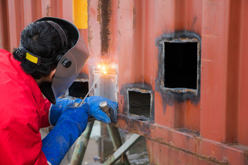 Worker repair container box by gas cutting and welding