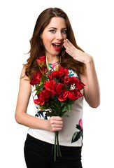 Beautiful young girl holding flowers making surprise gesture