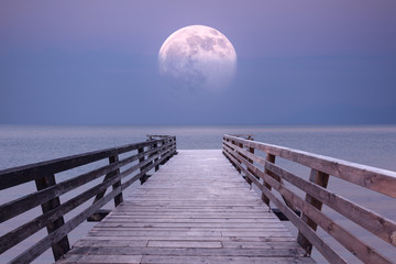 Volle maan en uitkijkplatform bij schemering op zee