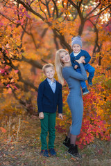 Fototapeta premium Mother lady womanwithTwo handsome cute brothers sitting on pumpkin in autumn forest alone