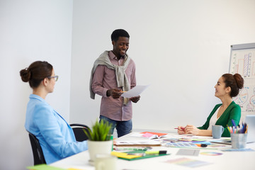 Young employees brainstorming and consulting about specific moments of their report