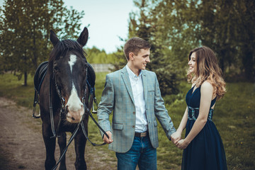 Couple in love walking in the woods with a horse.