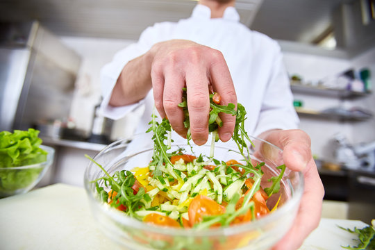 Chef mixing salad ingredients in bowl