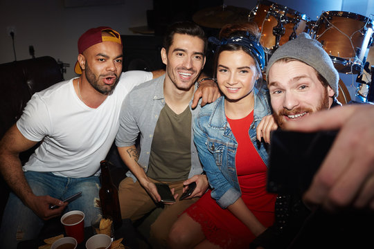 Group of modern trendy people chilling at night club party, posing for selfie photo and having fun