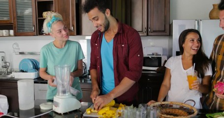 Young Man Chopping Pineapple, Woman Put Ice In Blender People Group Talking Prepare Healthy Smoothie Two Couples In Kitchen Cooking Together Meal Slow Motion 60