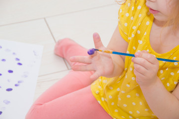 the child draws with a brush in hand with paint.