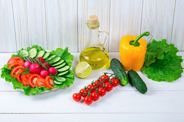 Cucumbers, radish, tomatoes cherry, olive oil, herb and spices on old white wooden background. Set for healthy foods. Ingredients for salad.