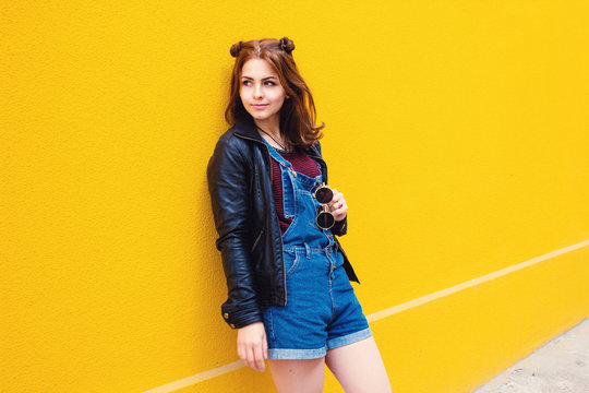 Beautiful girl in denim overall. Yellow background