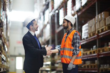 Business partner greeting warehouse worker in large-scale storage