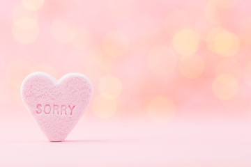 Pastel colored candy hearts in a bokeh background.