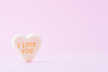 Pastel colored candy hearts in a bokeh background.