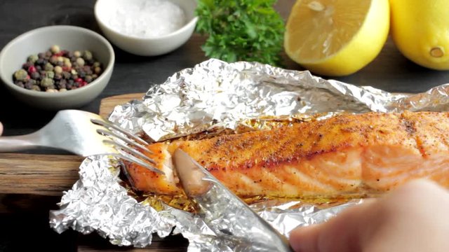 Video clip of food. A piece of fresh salmon wrapped in falgu on a white plate with Lemon, salt and pepper. Grey stone background. Real time.