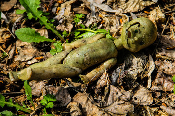 Abandoned old broken doll in the forest