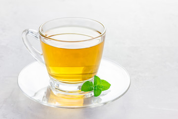 Herbal mint tea in a glass cup with fresh peppermint on background, horizontal, copy space
