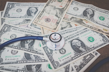 Stethoscope on dollar banknote money on wooden background