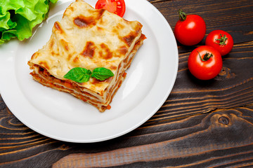 Portion of tasty lasagna on wooden backgound