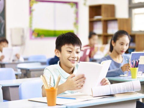 happy asian pupil studying in class