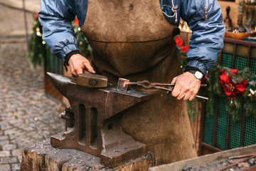 Blacksmith working metal with a hammer on the anvil in the forge