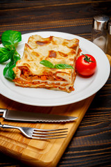 Portion of tasty lasagna on wooden backgound