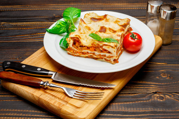 Portion of tasty lasagna on wooden backgound