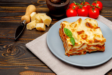Portion of tasty lasagna on wooden backgound