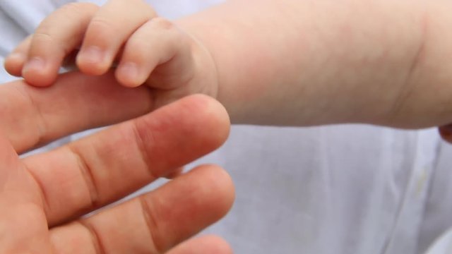 Closeup of baby hand into parents hands.