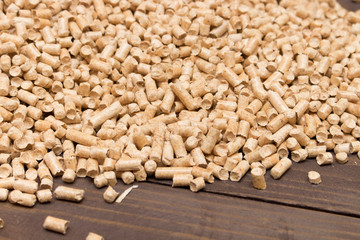 Wood pellets spill out of the packaging on wooden background . Biofuels. The cat litter .