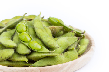Green soybean with seeds (Vegetable soybean) boiled in wooden plate on white