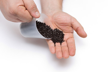 Plastic pellets spilled out of the measuring Cup on a man's hand. Colorant for plastics. Pigment in the granules, polymeric dye.