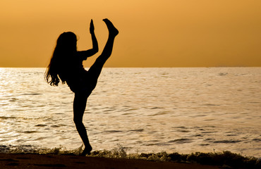 Niña entrenando artes marciales al amanecer en la playa
