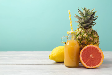 Pineapple, juice and grapefruit on wooden table over mint background. Summer detox diet concept