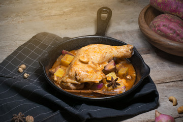 Low key of image of Chicken thighs in a cast iron skillet and sweet potato on wooden background