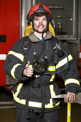 Portrait of a young fireman on the background of a fire truck