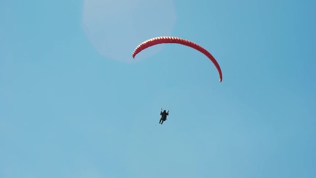 The paraglider in the sky, flies in the air streams. An extreme hobby for wealthy men. Modern equipment