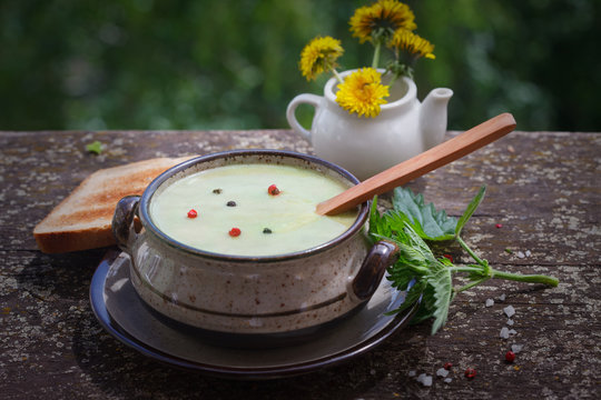 Nettle cream soup with black and red pepper. Nettle soup with toast bread on wooden background.