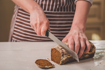 Woman cutting bread on wooden board. Bakehouse. Bread production.
