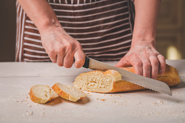 Woman cutting bread on wooden board. Bakehouse. Bread production.
