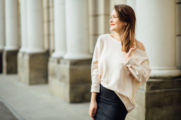 Slim elegant woman with red lips in a beige coat and black skirt brunette with long legs near the...