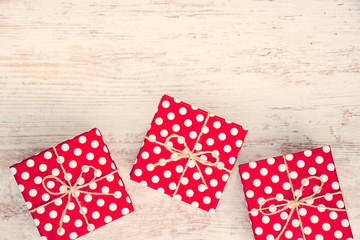Red dotted gift boxes scattered over white wood background. Vintage effect.