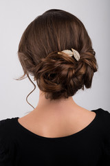 Assembled formal hairstyle dark hair decorated with a crest in the form of sheets, back view