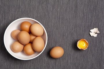 the Eggs in a white plate, one whole egg next to broken egg on the table