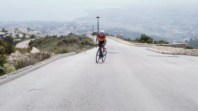 Healthy pretty female athlete cycles professional road bicycle outdoors on a fitness workout training shot on a steadicam